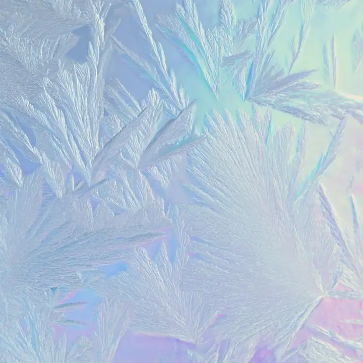 Frost crystals spreading across pale glass