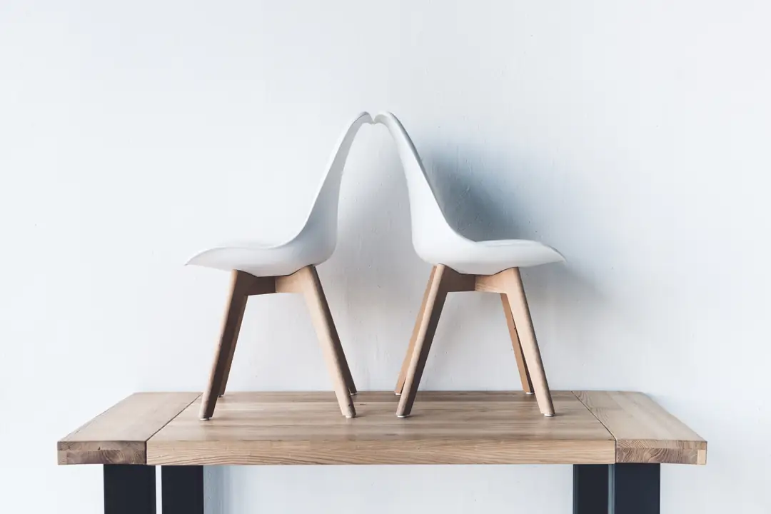 Two white chairs facing away from each other on a wooden platform