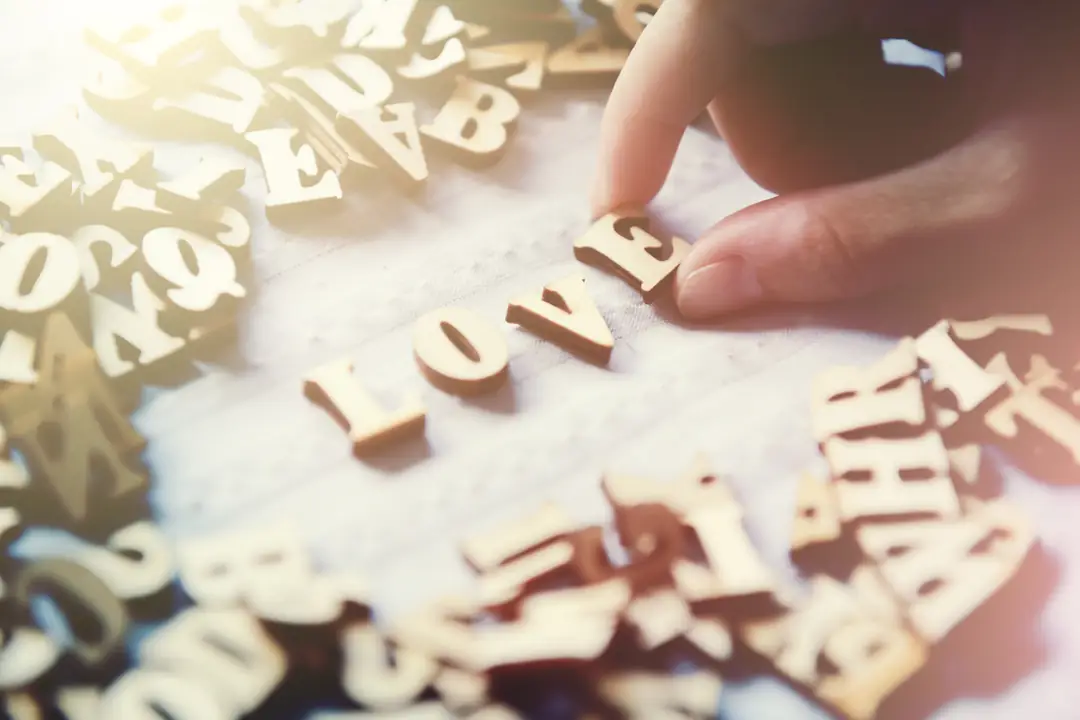 A hand arranging wooden letters to spell love