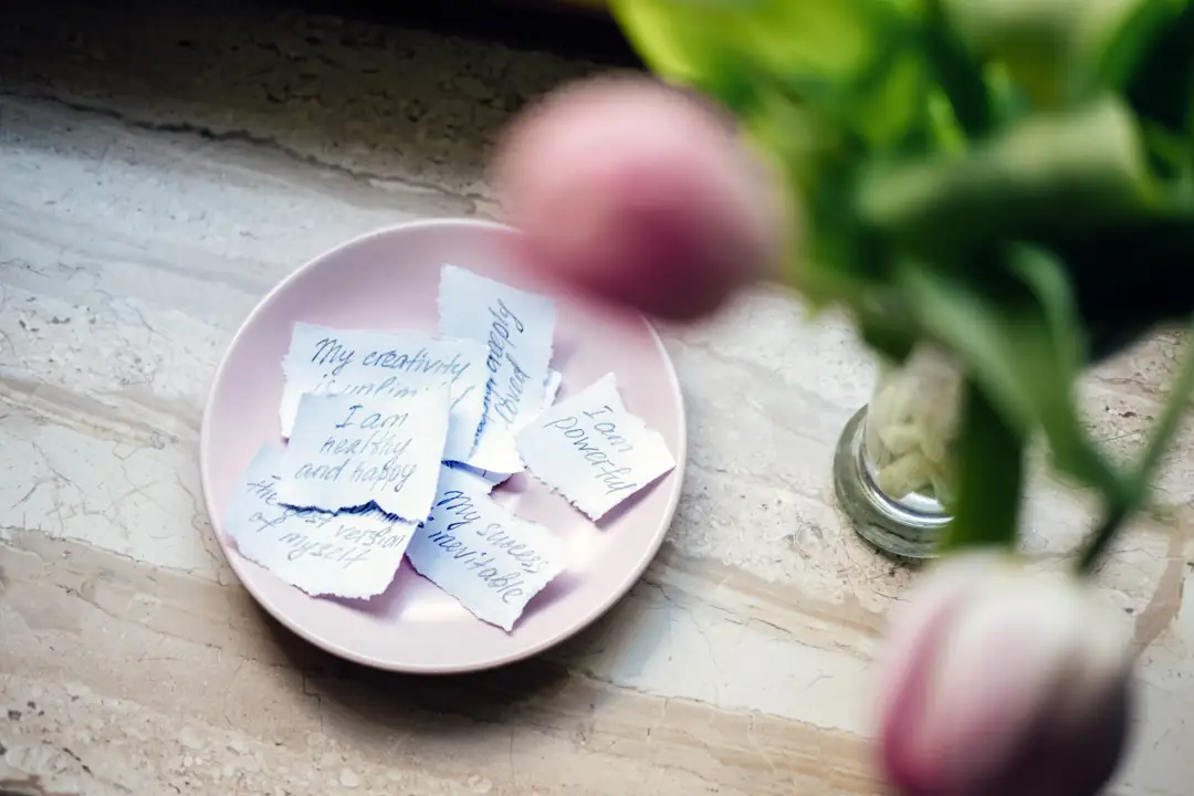 Handwritten notes on a pink plate beside flowers